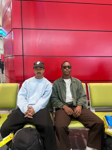 Two Earthians on yellow seats against a red wall