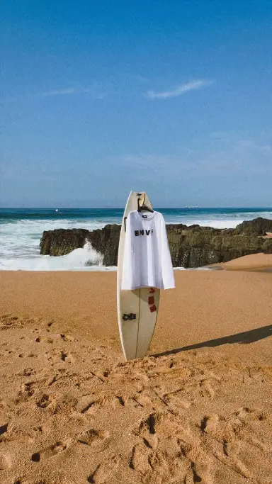 The EMVŸ Wave long sleeve draped on a surfboard on the beach