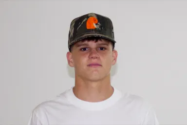 EMVŸ camo cap with the orange embroidered mark, worn front-on