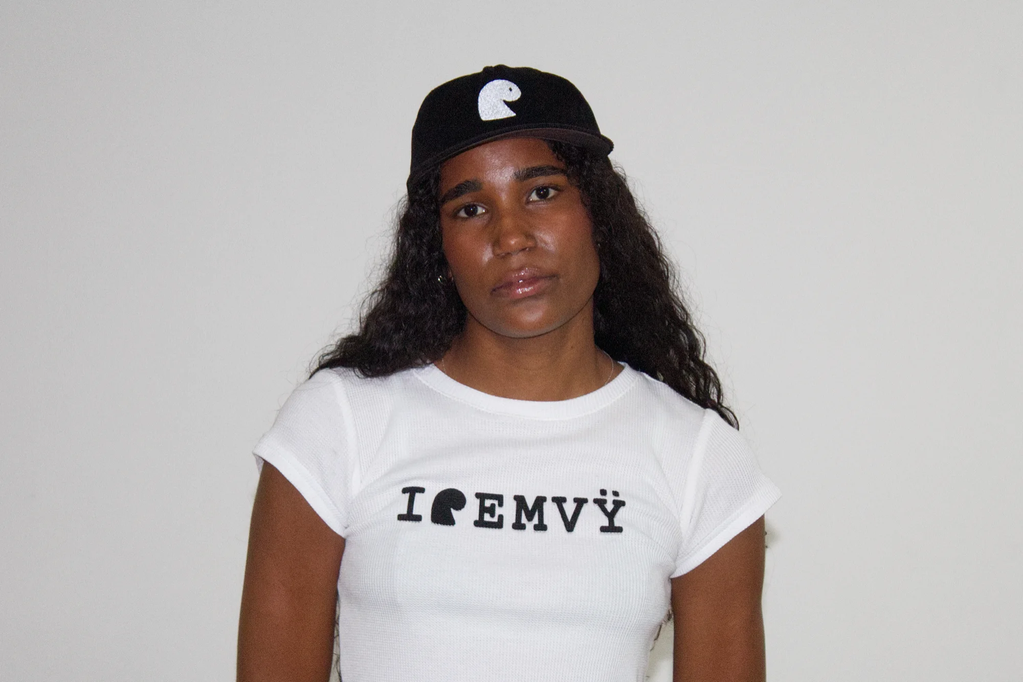 Black corduroy cap with the white embroidered EMVŸ mark, worn front-on