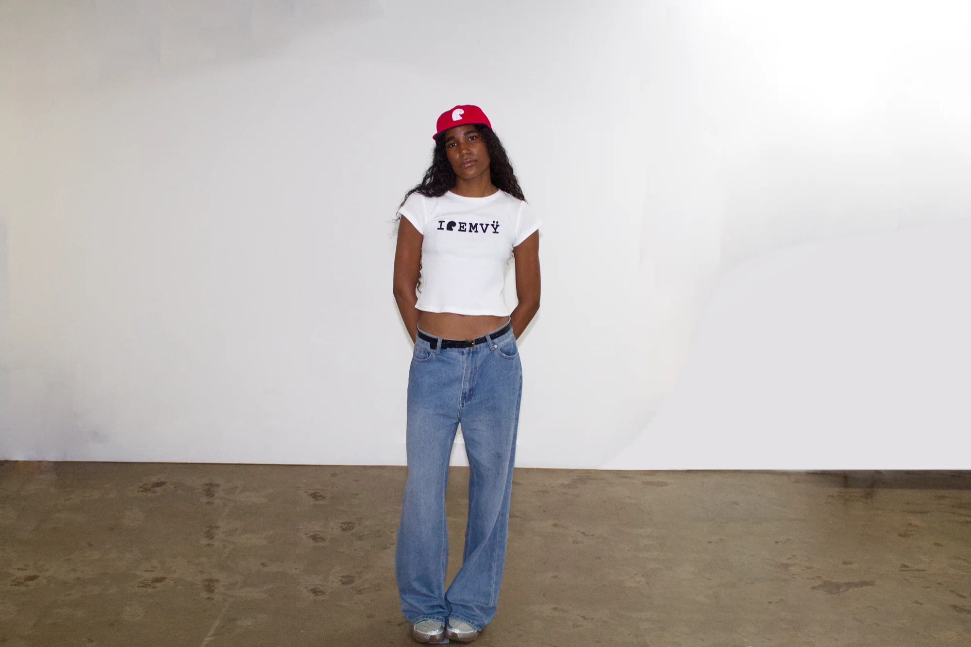 Red corduroy EMVŸ cap full length, worn with the white baby tee
