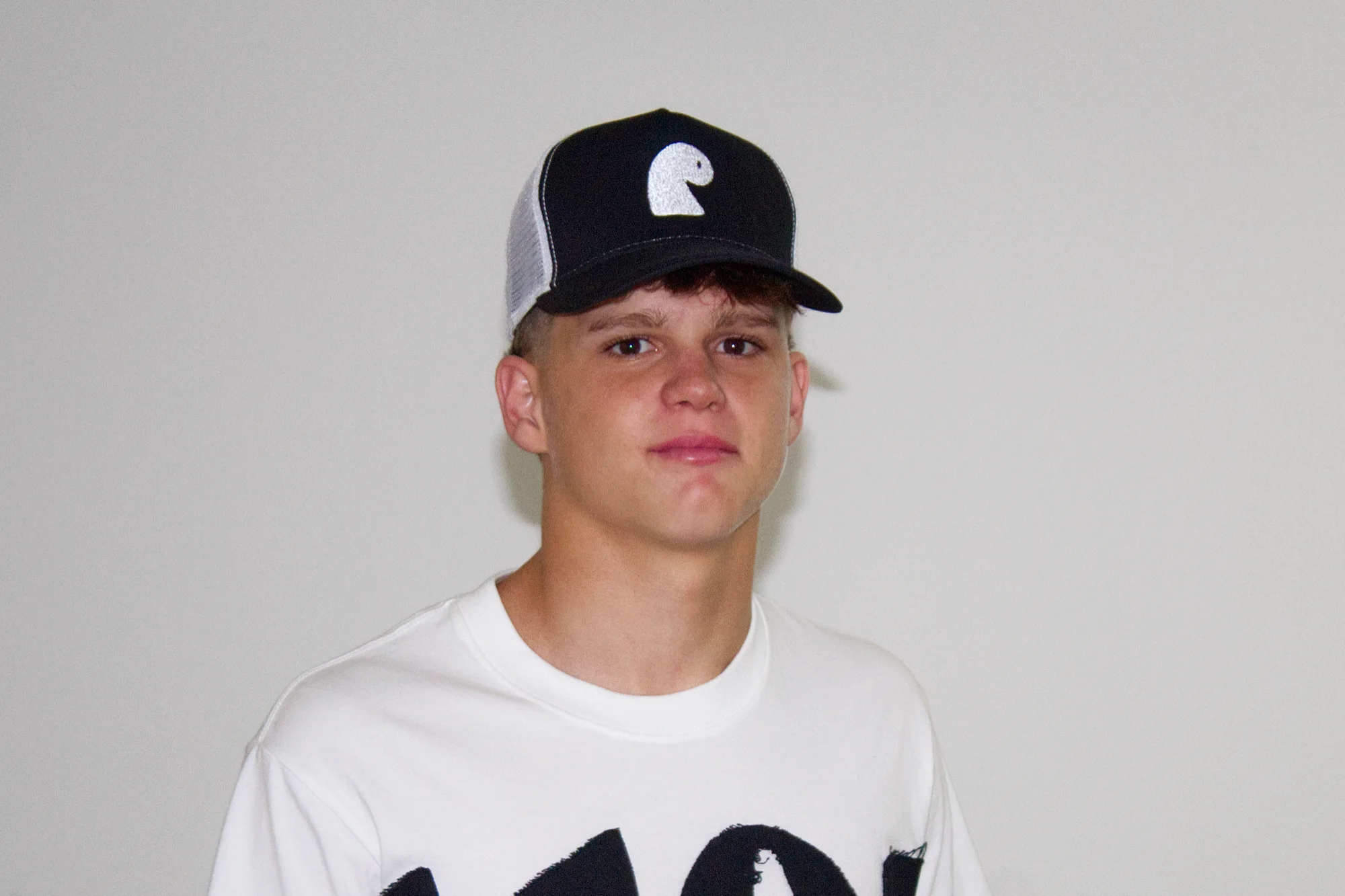 Black trucker cap with the white embroidered EMVŸ mark, worn front-on