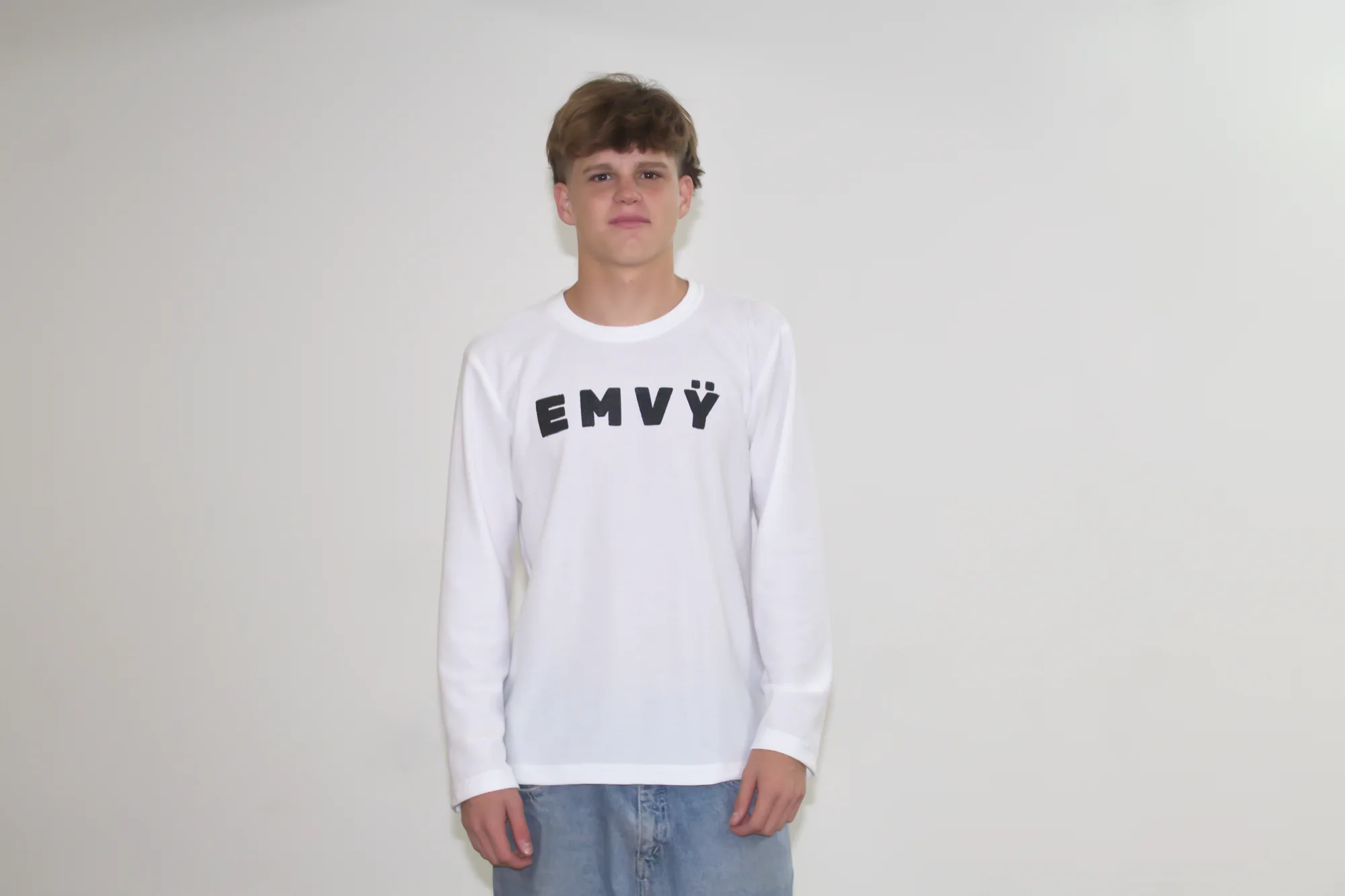 White EMVŸ waffle longsleeve worn front-on, EMVŸ across the chest